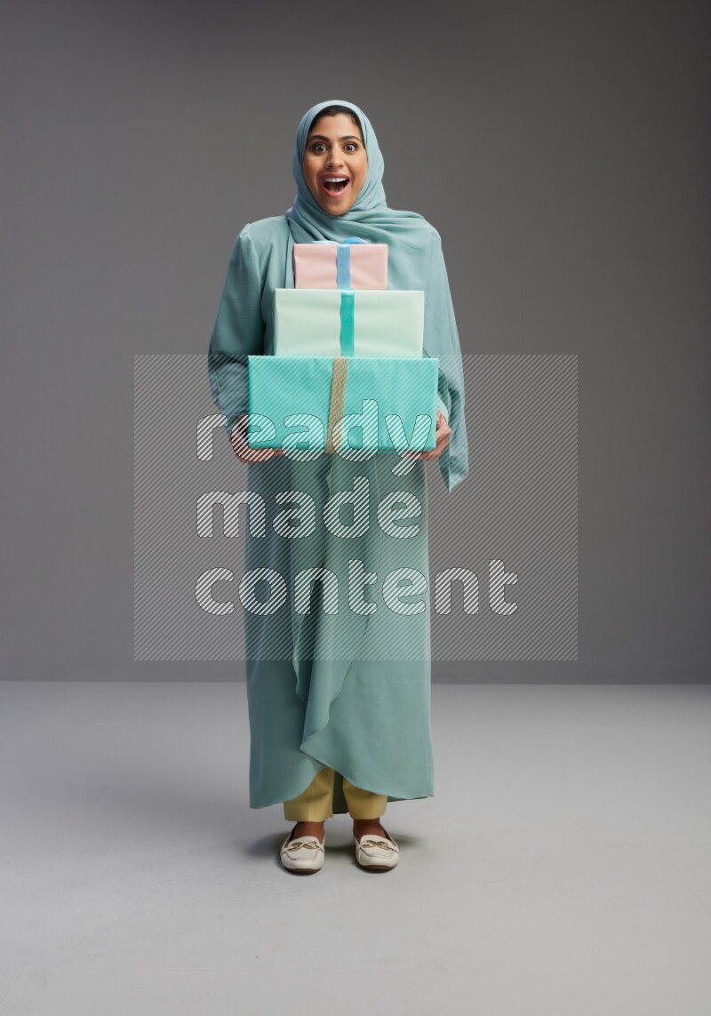 Saudi Woman wearing Abaya standing holding gift box on Gray background