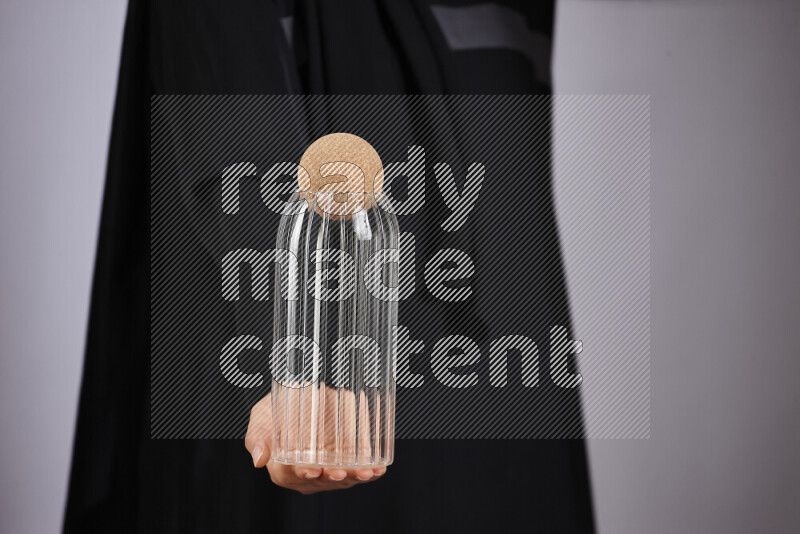 A woman in black abaya holding different glassware in different positions