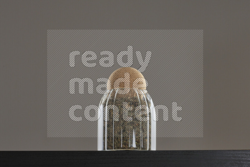Dried basil in a glass jar on black background