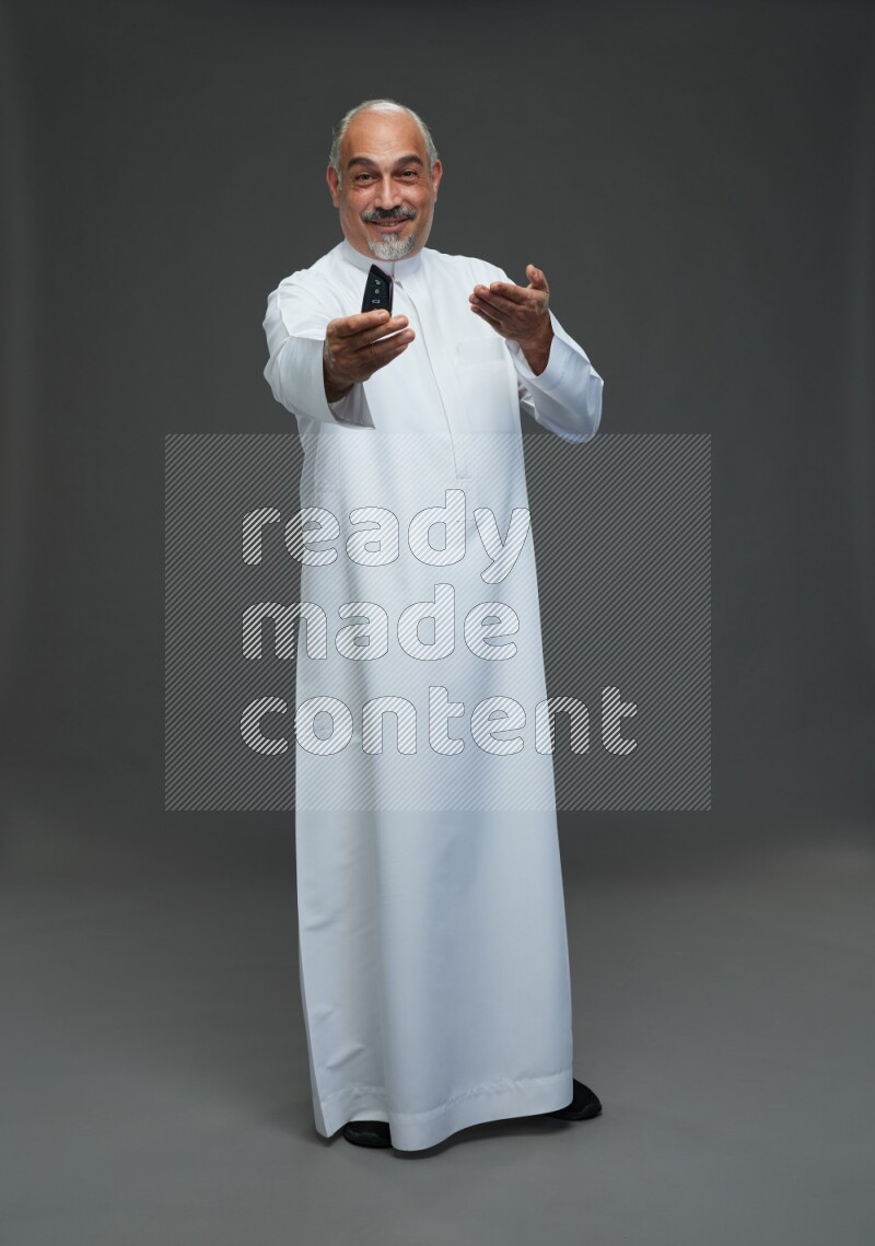 Saudi man without shomag Standing holding car key on gray background
