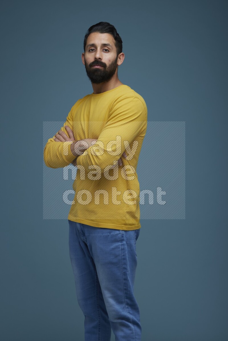 Man posing in a blue background wearing a yellow shirt