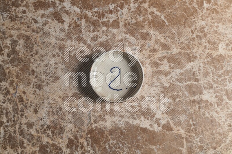 A multicolored pottery bowl on beige marble background