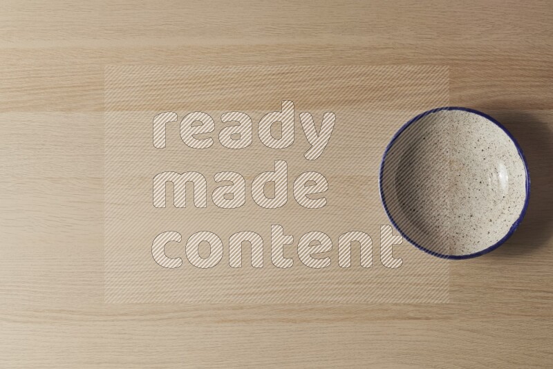 A multicolored pottery bowl on light wooden background