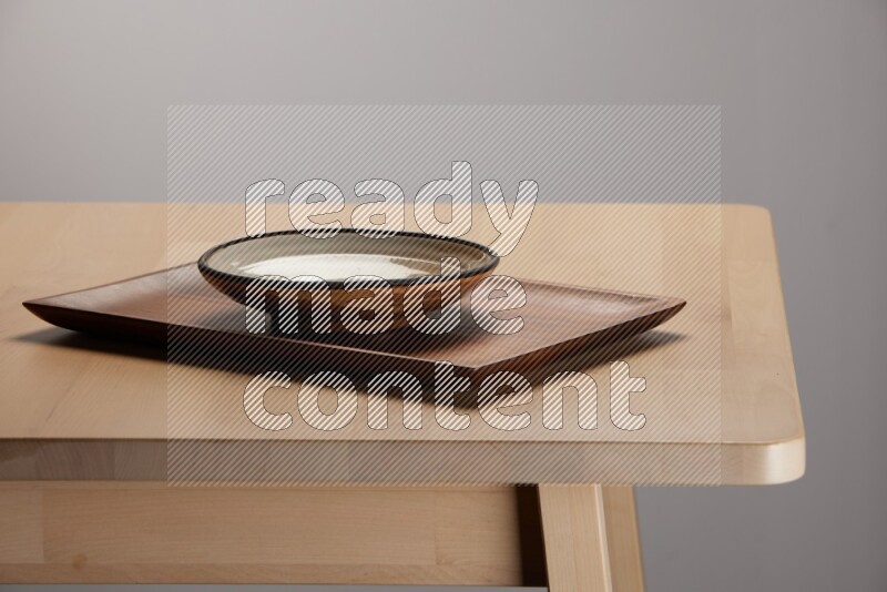multicolored plate on a rectangular wooden tray on the edge of wooden table