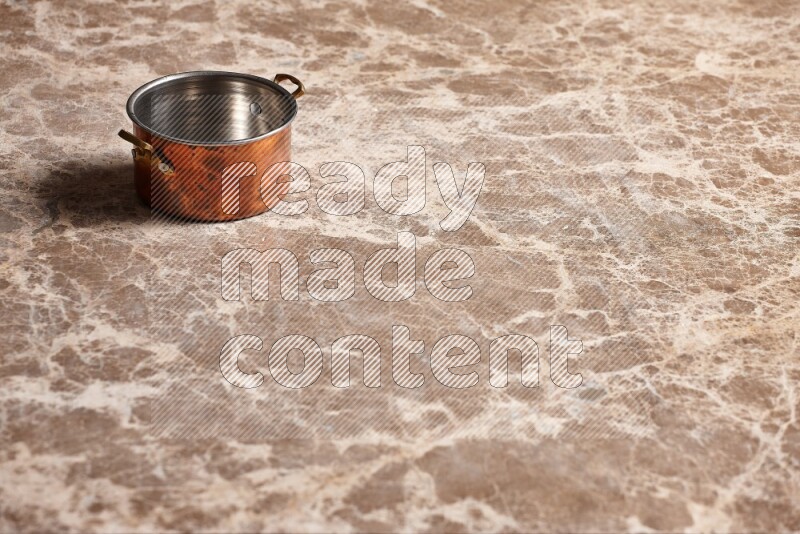 A small copper pot on beige marble background