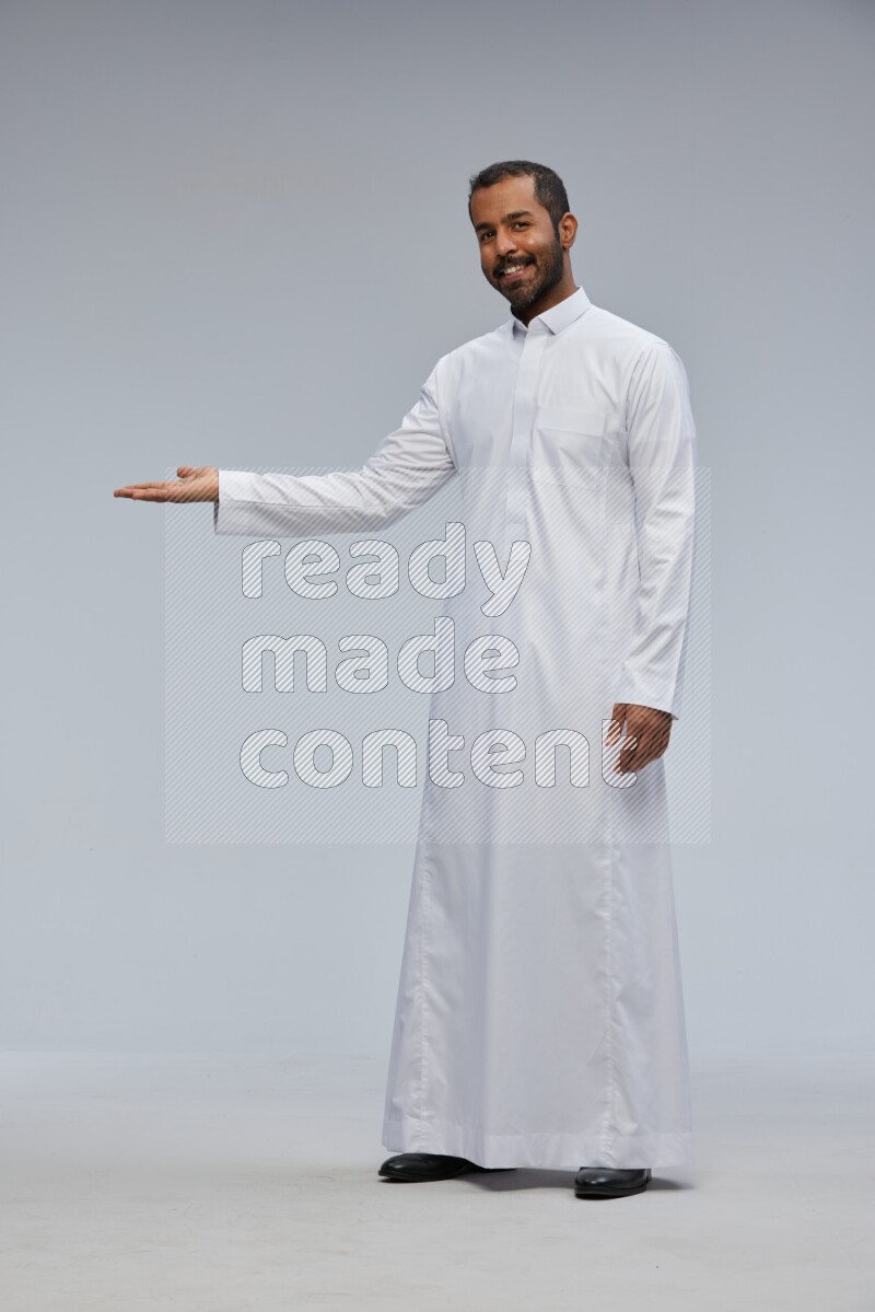 Saudi man Wearing Thob standing interacting with the camera on Gray background