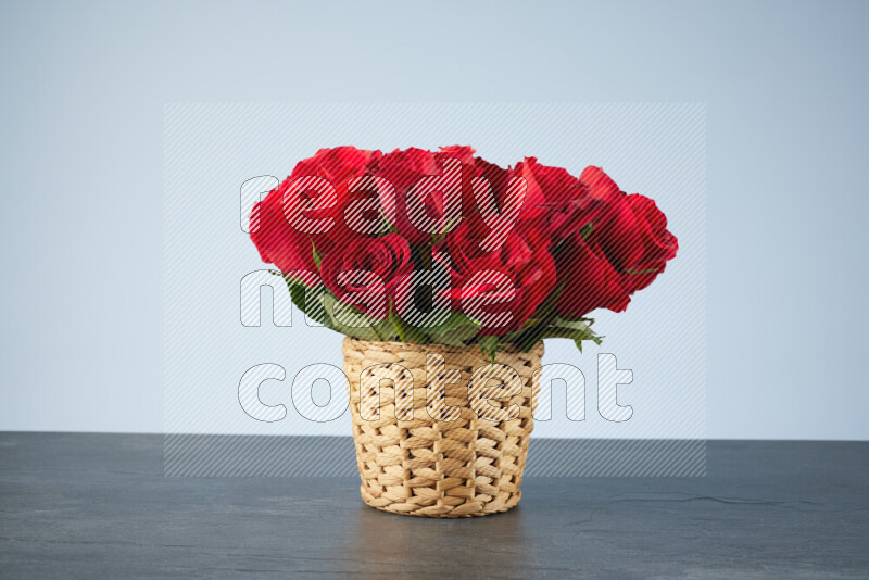 Vibrant red roses in a wicker basket on black marble background