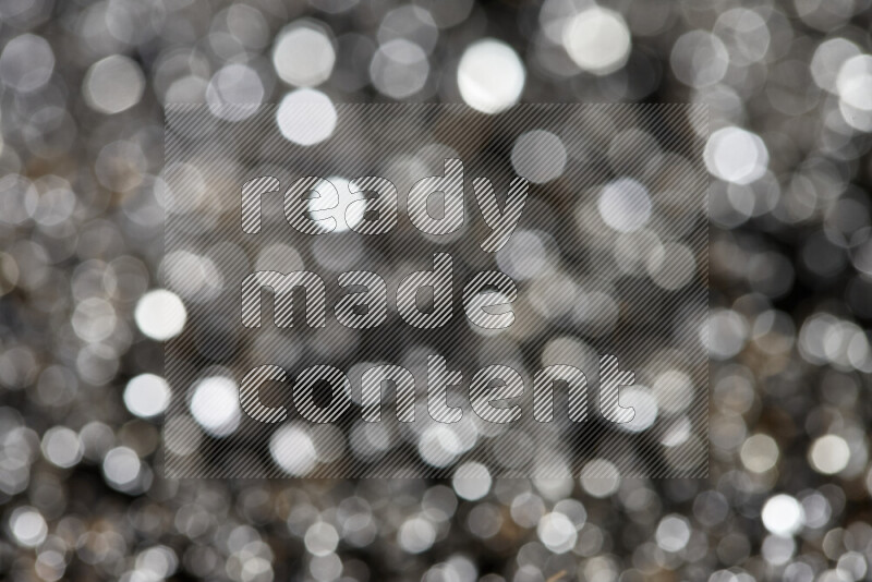 Silver shimmering fragments of glass scattered on a black background