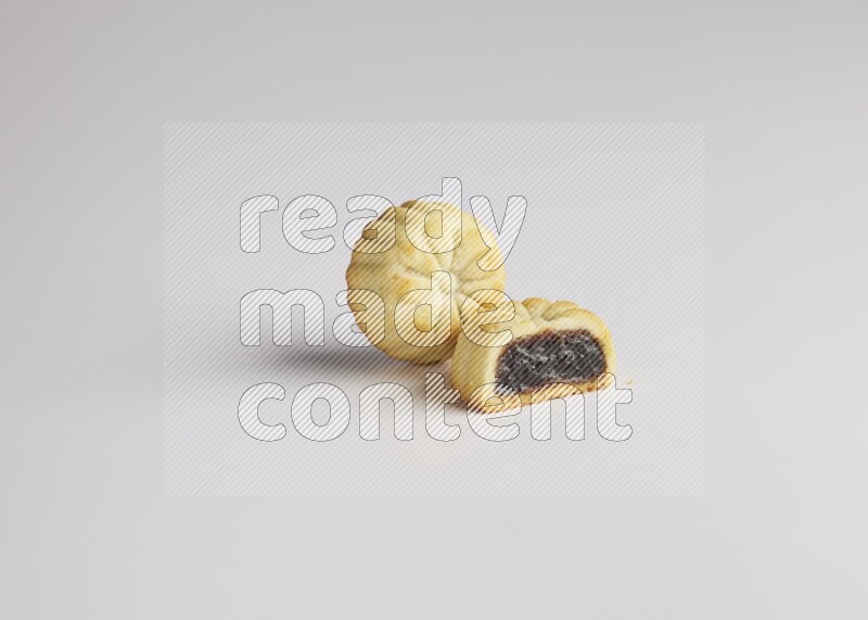 Two Pieces of Maamoul filled with date one of them is cut direct on white background