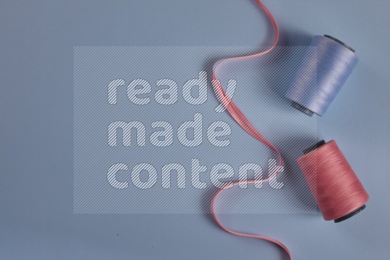 A pink collection of sewing and tailoring tools arranged on a blue background