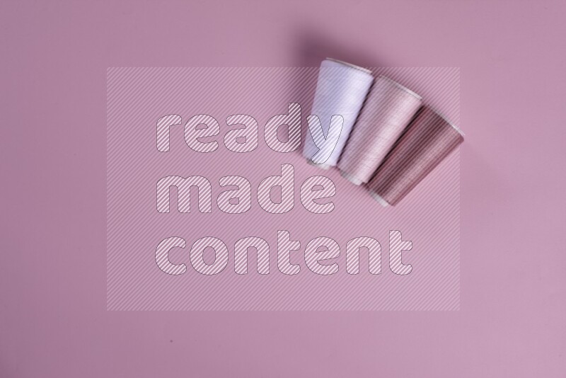 مجموعة من أدوات الخياطة والتفصيل بيضاء وزهرية اللون على خلفية زهرية