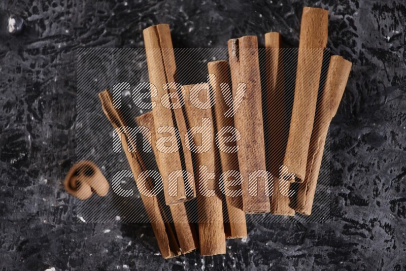 Cinnamon sticks on a textured black background