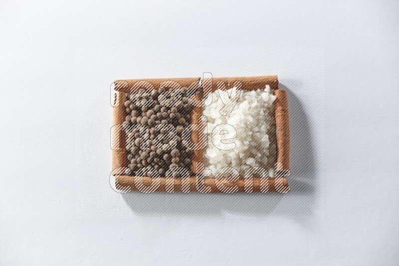 2 squares of cinnamon sticks full of white salt and allspice on white flooring
