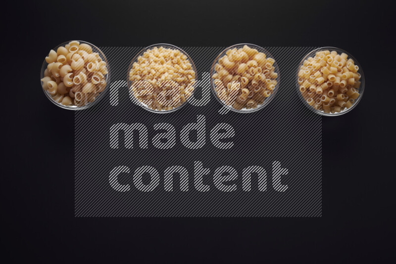 أنواع مختلفة من المعكرونة في وعاء زجاجي علي خلفية سوداء