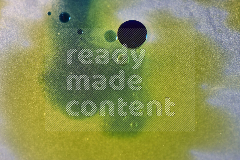 Close-ups of abstract yellow, blue and green watercolor drops on oil Surface on white background