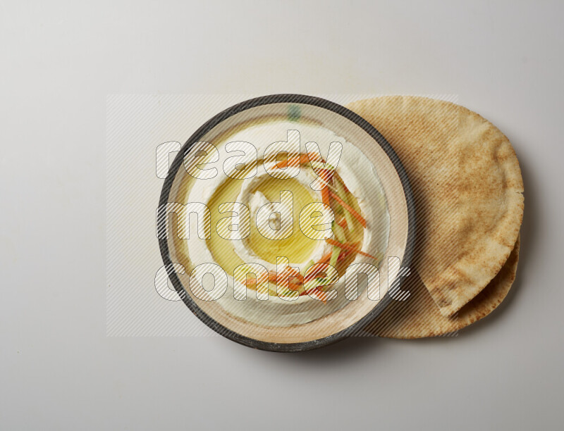 Lebnah garnished with sliced carrots &cucumber in a pottery plate on a white background