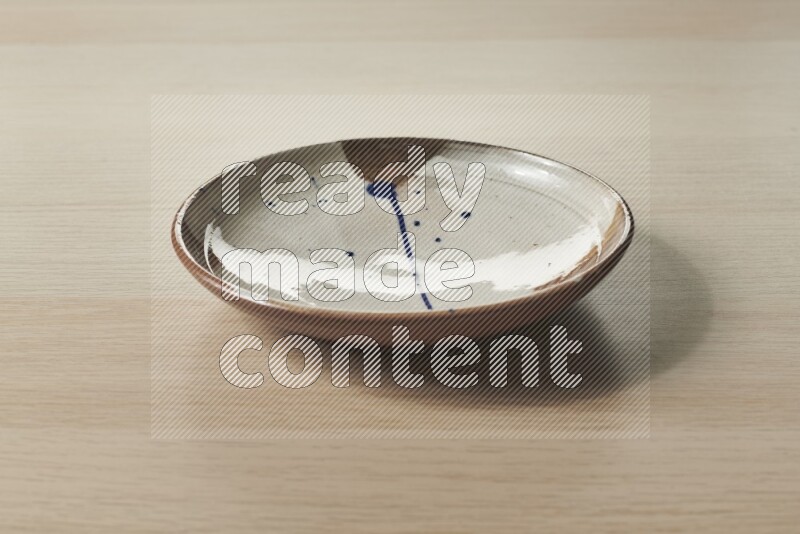 A multicolored pottery plate on light wooden background