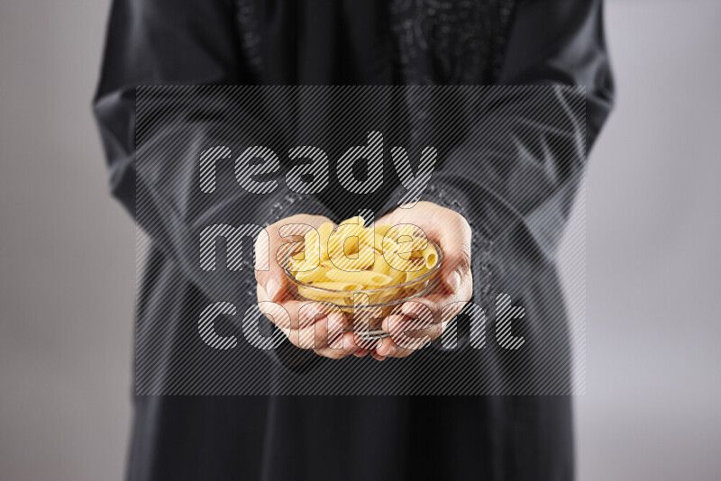 Woman in abaya holding different kinds of pasta in different positions