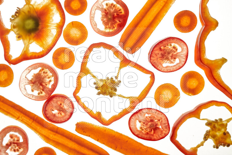 Mixed vegetables and fruits slices on illuminated white background