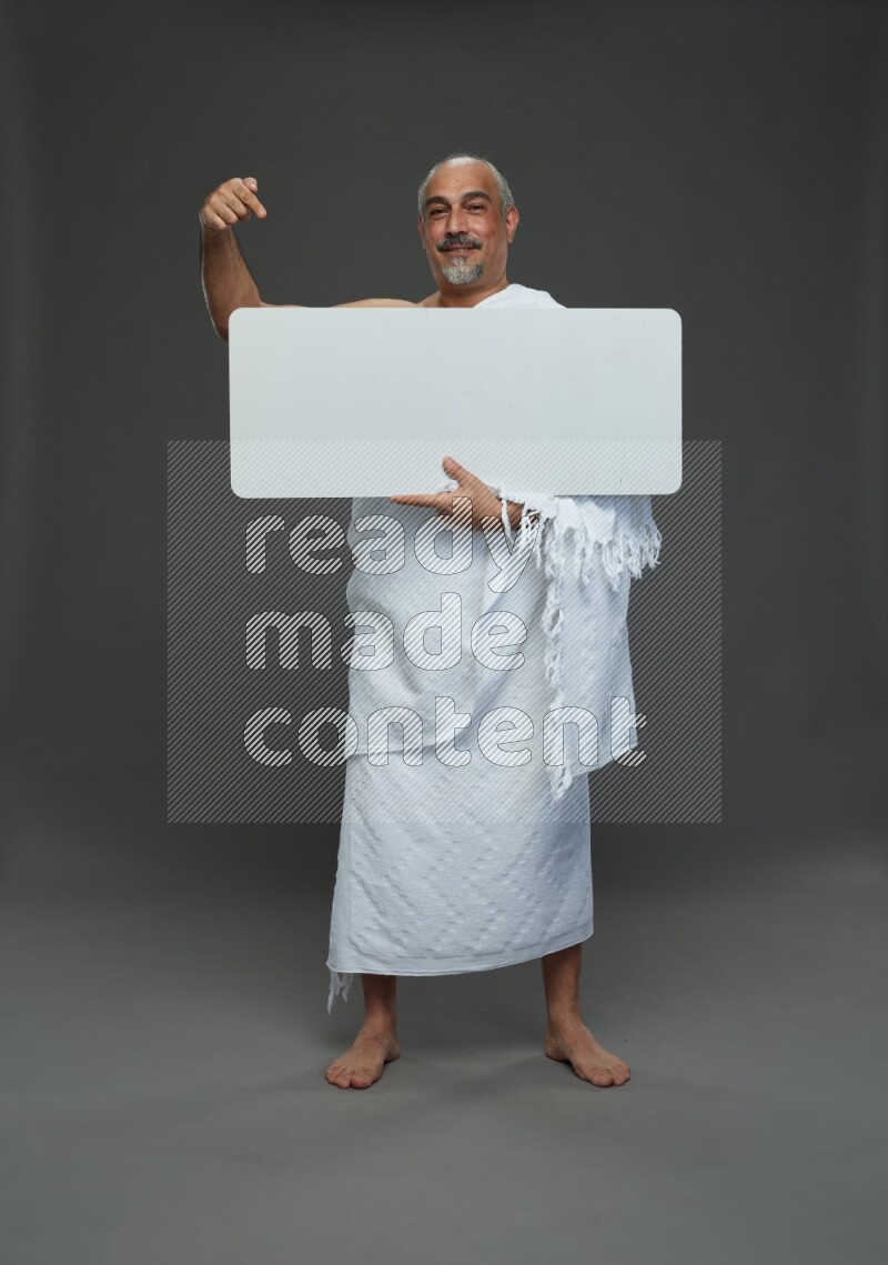 A man wearing Ehram Standing holding social media sign on gray background