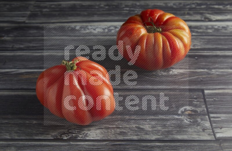45 degree two heirloom tomato on a textured grey wooden background