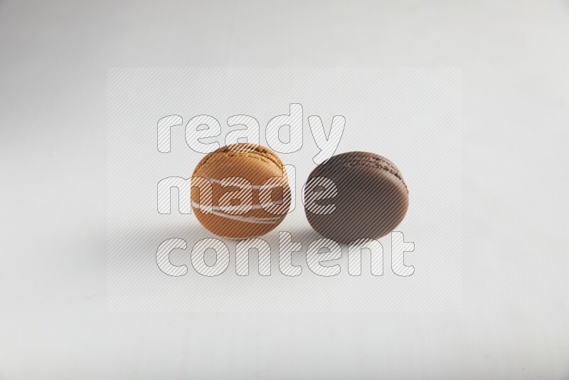 45º Shot of of two assorted Brown Irish Cream, and Brown Dark Chocolate macarons on white background