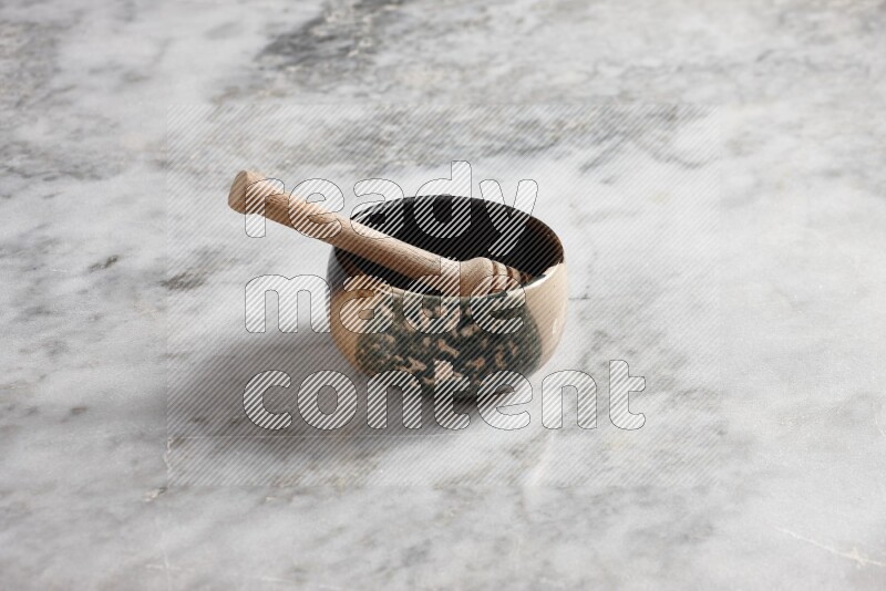 Multicolored pottery bowl with wooden honey dipper in it on grey marble background