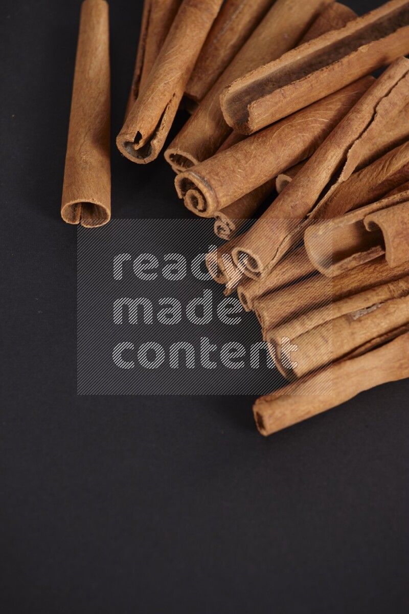 Cinnamon sticks stacked on black flooring