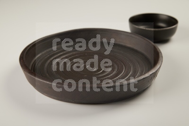 black pottery plate and black bowls on white background
