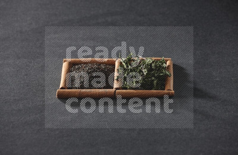 2 squares of cinnamon sticks full of tea and dried mint leaves on black flooring