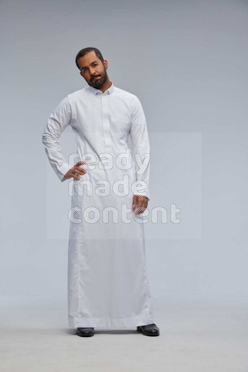 Saudi man Wearing Thob standing interacting with the camera on Gray background