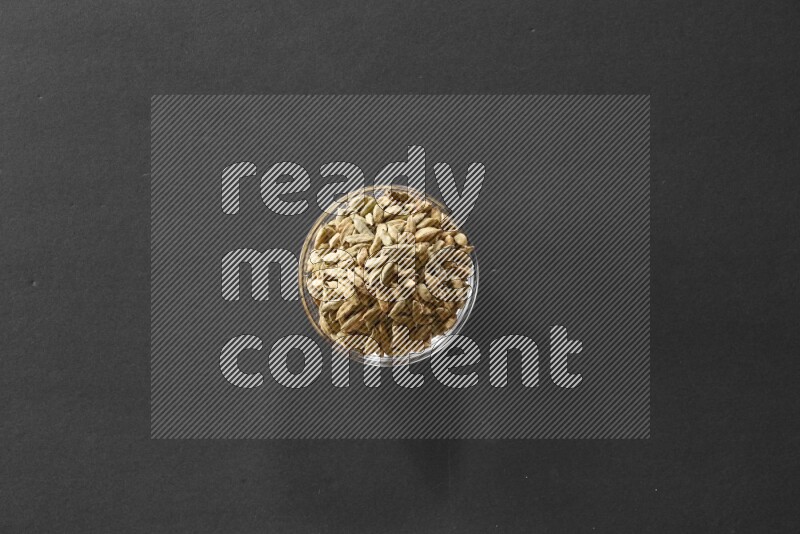 A glass bowl full of cardamom on black flooring