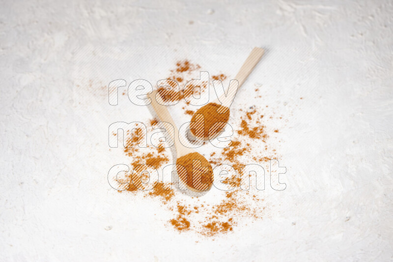 Two wooden spoons full of ground paprika powder on white background