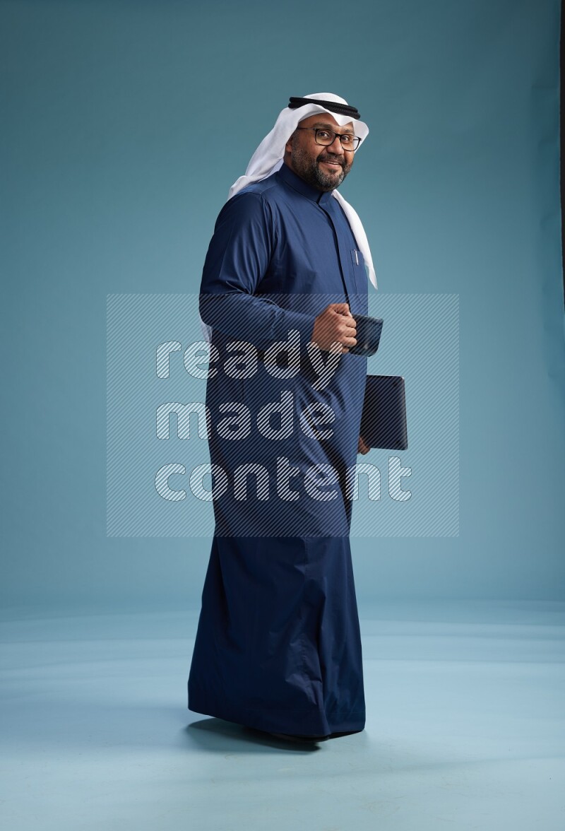 Saudi Man with shimag Standing drinking coffee on blue background
