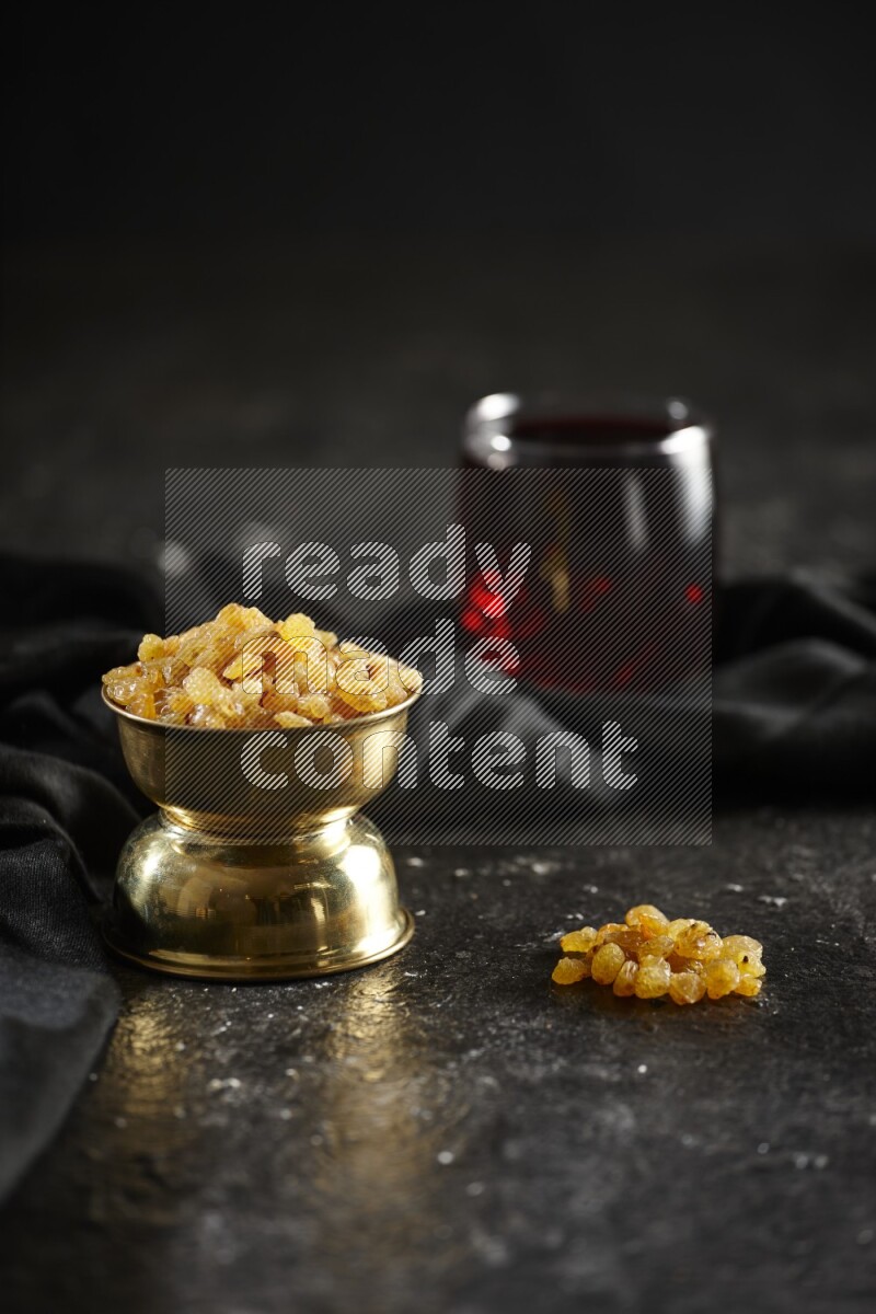 Dried fruits in a metal bowl with Hibiscus and a napkin in a dark setup