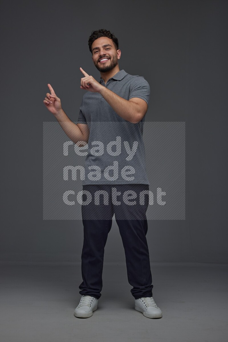 A man wearing casual standing and making multi hand gestures eye level on a gray background