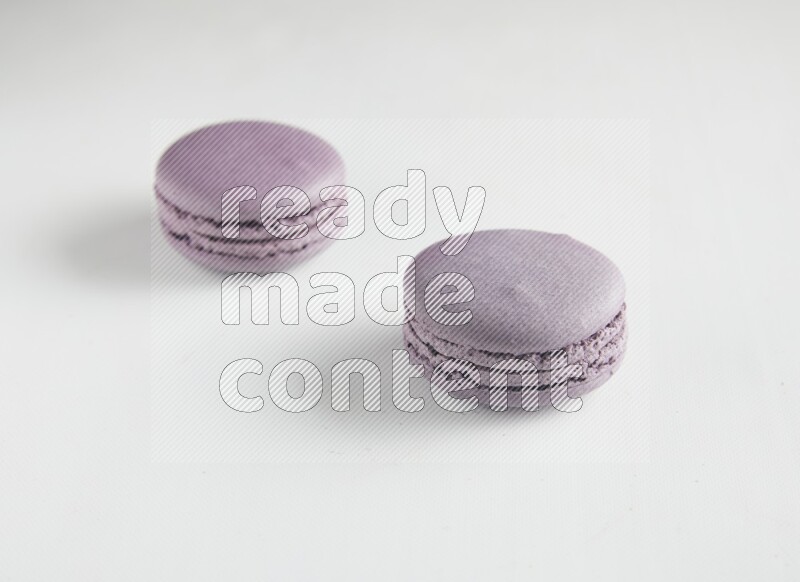 45º Shot of two Purple Blueberry macarons on white background