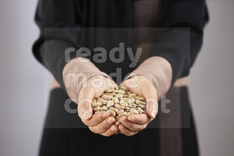 Woman in abaya holding different kinds of legumes in different positions