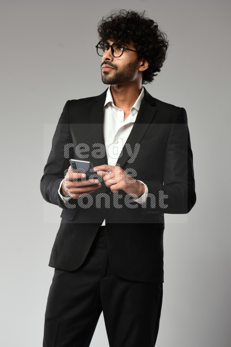 A man wearing formal standing and browsing on the phone on white background