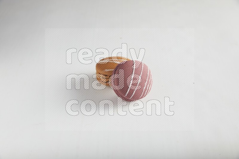 45º Shot of of two assorted Brown Irish Cream, and Red Poppy Flower macarons on white background