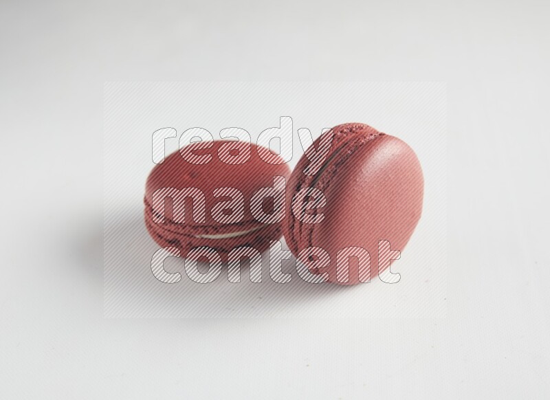 45º Shot of two Red Velvet macarons on white background