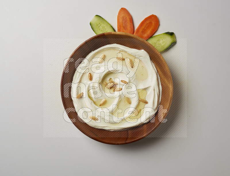 Lebnah garnished with pine nuts in a wooden plate on a white background