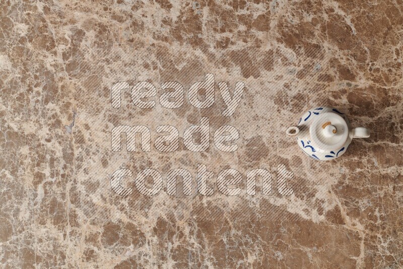 A pottery teapot on beige marble background