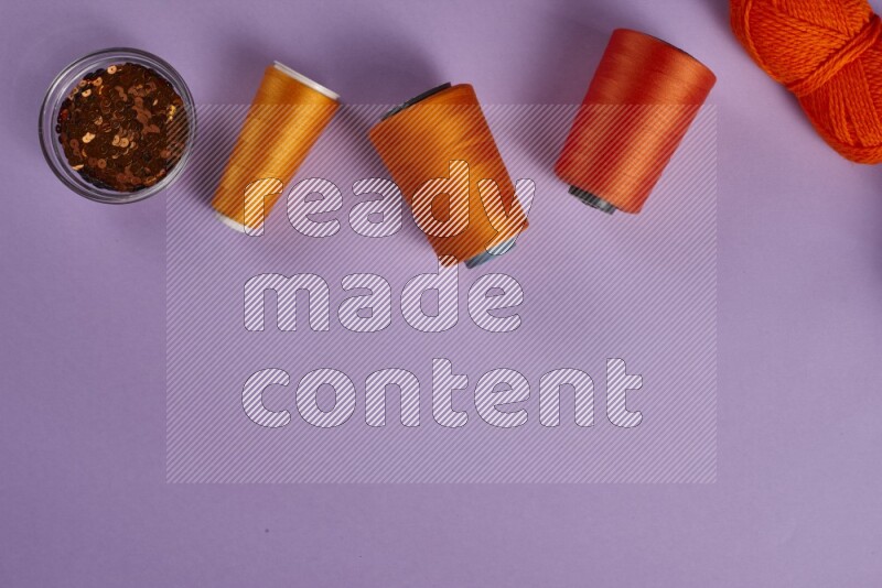 An orange collection of sewing and tailoring tools arranged on a purple background
