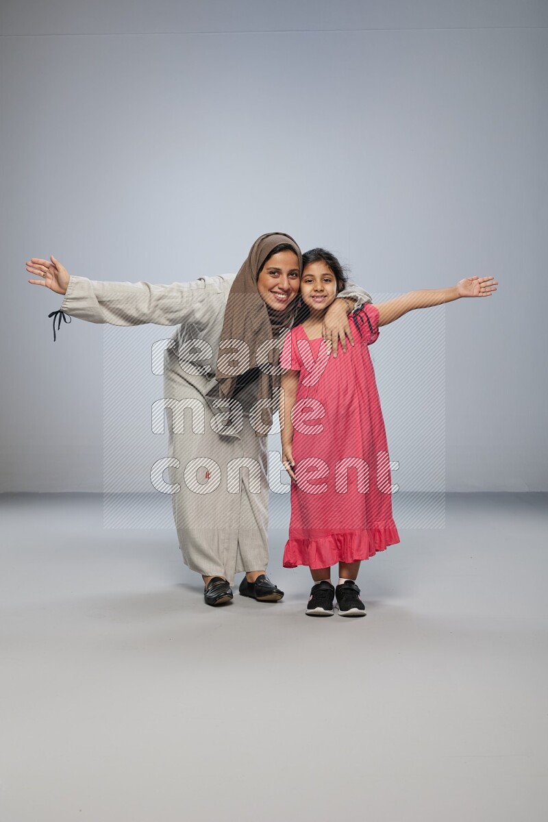 A girl and her mother interacting with the camera on gray background