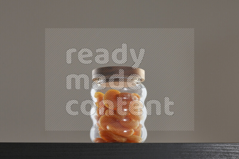 Dried apricots in a glass jar on black background