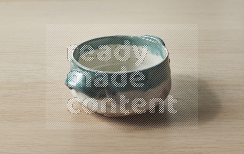 وعاء فخاري متعدد الألوان على خلفية خشبية فاتحة