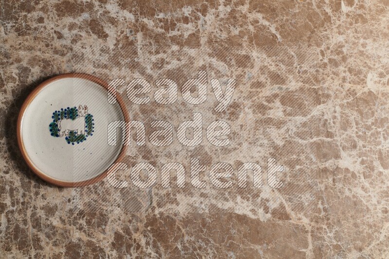 A decorative pottery plate on beige marble background