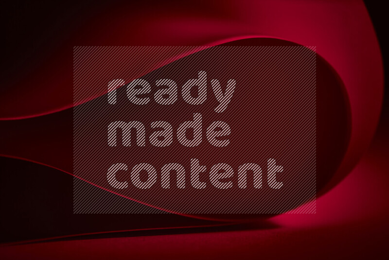 An abstract art piece displaying smooth curves in red gradients created by colored light