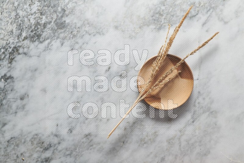 Wheat stalks on multicolored pottery plate on grey marble background